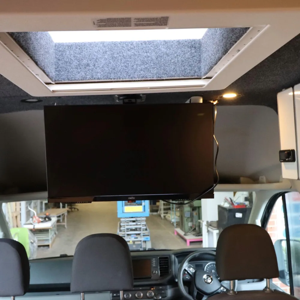 A small TV mounted to the ceiling of a camper.