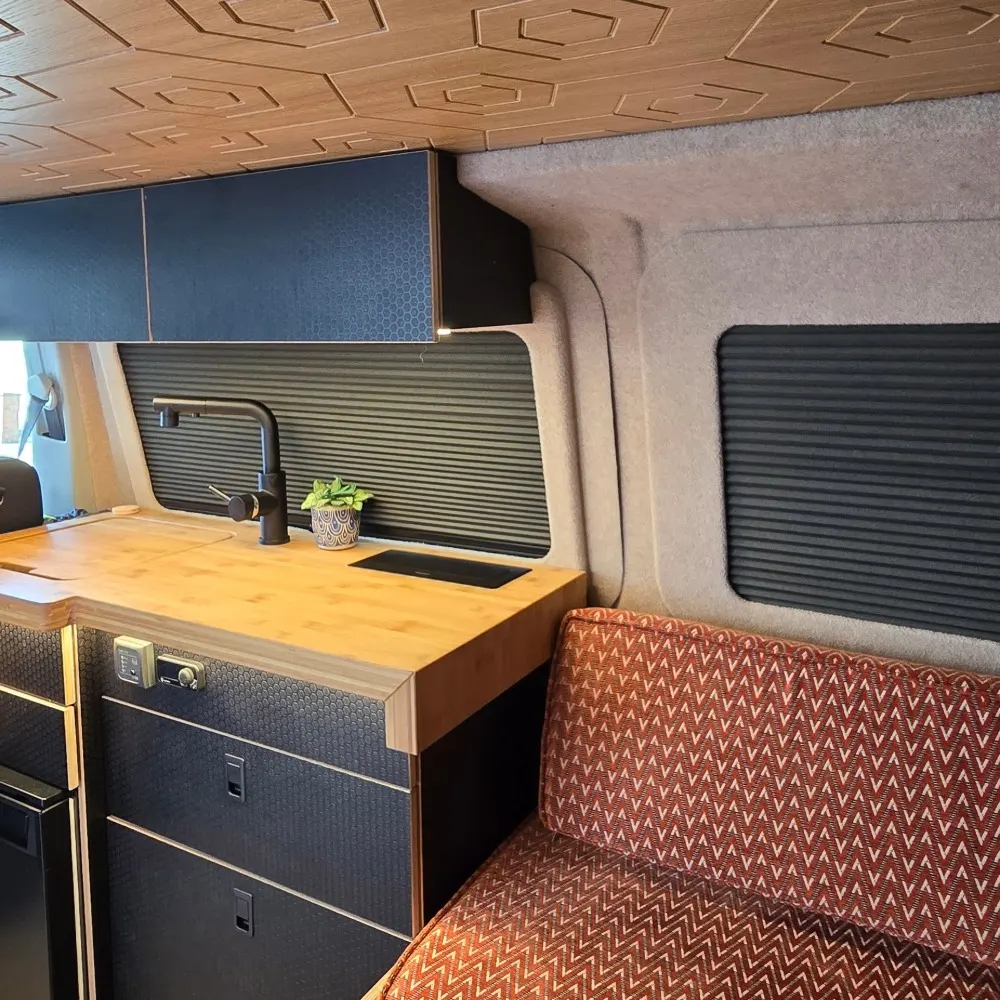 A wood finish camper kitchen next to orange seating.