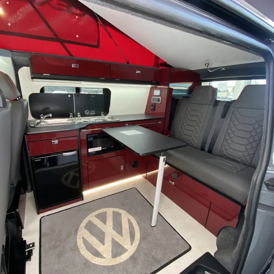 A camper van interior with a VW rug and a red and grey colour scheme.