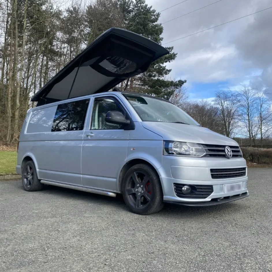 A silver WV camper van with a pop-top roof.