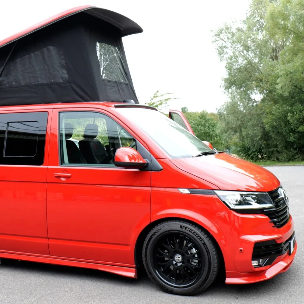 A red VW camper van with a pop-top roof and body kit.